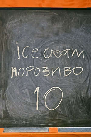 price for ice-cream writed by white chalk on blackboard on ukrainian and english languages, trade details の写真素材