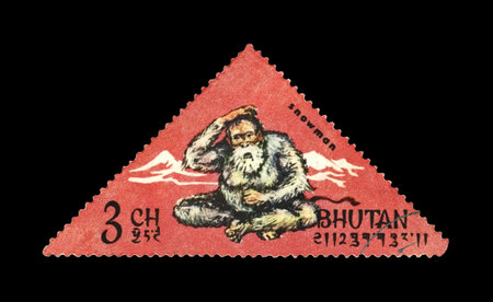 BHUTAN - CIRCA 1966: canceled stamp printed in Bhutan shows snowman and mountains, circa 1966. vintage postal stamp isolated on black background.のeditorial素材