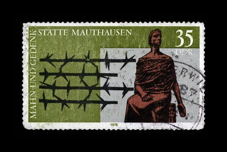 DDR - CIRCA 1978: vintage canceled stamp printed in DDR shows Mauthausen concentration camp Memorial, barbed wire, circa 1978. vintage postal stamp isolated on black background.のeditorial素材