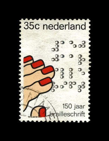 fingers reading code by Louis Braille (1809-1852), famous educator, inventor of reading and writing system aka tactile code cipher for use by the blind or visually impaired people, circa 1975. vintage canceled post stamp printed in Netherlands isolated onのeditorial素材