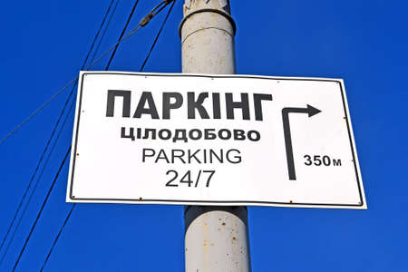 parking 24 hours as text on ukrainian language on metal pylon on blue sky in sunny day, environment diversityの写真素材