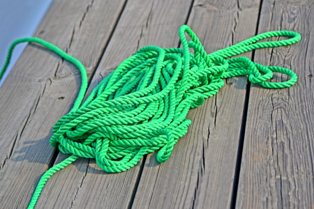 green skein rope heap closeup on vintage wooden surface (deck board), pier environment diversity