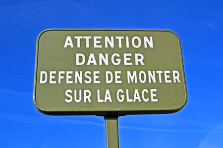 attention, danger defense to ride on the ice as text message on black board on blue skyの写真素材