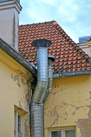 huge high metal pipe on tiled roof, modern industry diversity
