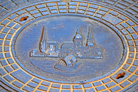 vintage metal sewage manhole closeup with Riga town emblem devoted to 800th city anniversary in August, 2001 on December 31, 2019 in Riga, Latviaのeditorial素材