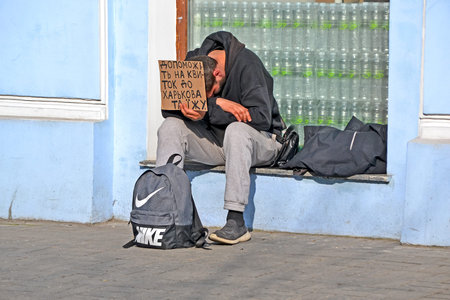 unknown unemployed tired sleeping young man in black suit asking for money for ticket and food on...