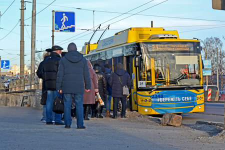 people waiting for boarding to the trolleybus during virus quarantine on March 25, 2021 in Kiev, Ukraine. Take care of yourself as blue message on Kievpastrans aka Kiyvpastrans transport.のeditorial素材