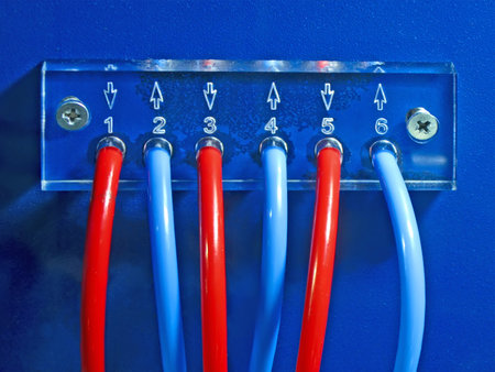 red and blue connected cables pack heap on blue transparent plexiglass control panel surface fixed with few screw closeup. color power electricity numbers conceptの写真素材