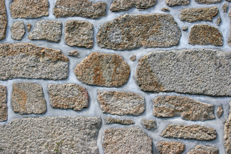 Ancient wall of granite stone repaired with fresh concrete
