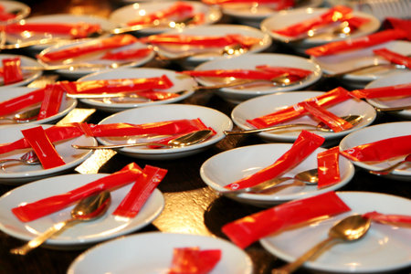 several coffee dishes with red sugar packets and spoons