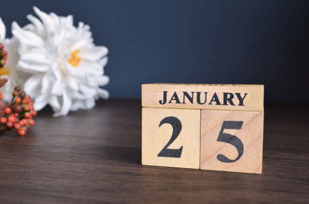 January 25, Date cover design with calendar cube and white Paeonia flower on wooden table and blue background.の写真素材
