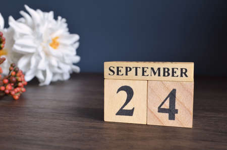 September 24, Date cover design with calendar cube and white Paeonia flower on wooden table and blue background.の写真素材