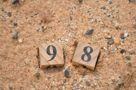 Number 98, rating, award, Cover design in natural concept with a number cube on sand background.の写真素材