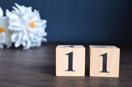 Number 11, rating, award, Empty cover design in natural concept with a number cube and peony flower on wooden table for a background.の写真素材