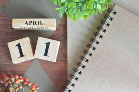 April 11. Date of April month. Number Cube with a flower and notebook on Diamond wood table for the background.の写真素材