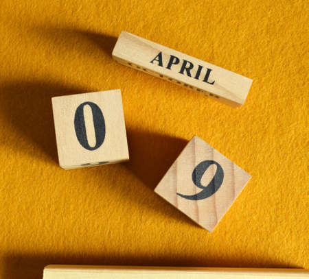 April 9, Wooden Calendar cube on yellow felt fabric for date icon background.の写真素材