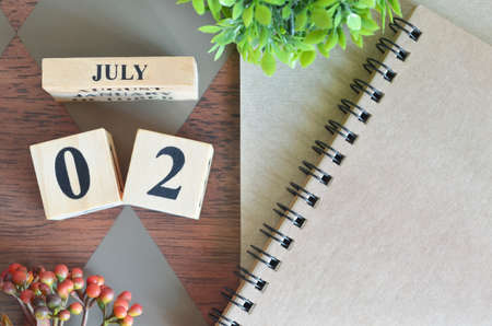 July 2,  Number Cube with a flower and notebook on Diamond wood table for the background.の写真素材