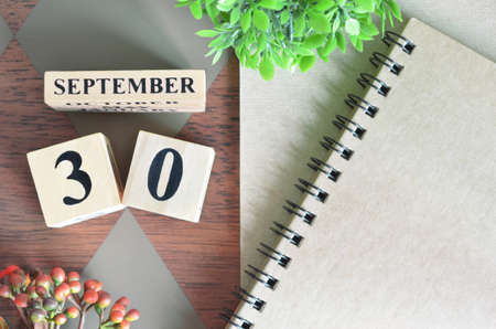 September 30. Date of September month. Number Cube with a flower and notebook on Diamond wood table for the background.の写真素材