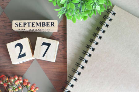 September 27. Date of September month. Number Cube with a flower and notebook on Diamond wood table for the background.の写真素材