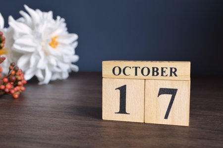 October 17, Date cover design with calendar cube and white Paeonia flower on wooden table and blue background.の写真素材