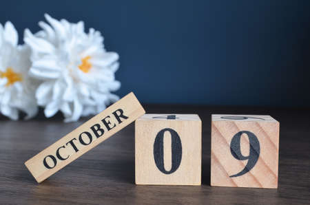 October 9, Date cover design with calendar cube and white Paeonia flower on wooden table and blue background.の写真素材
