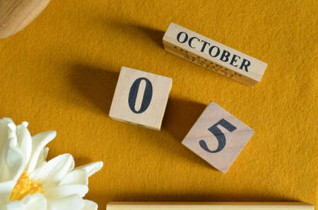 October 5, Wooden Calendar cube on yellow felt fabric with peony flower for date icon background.の写真素材