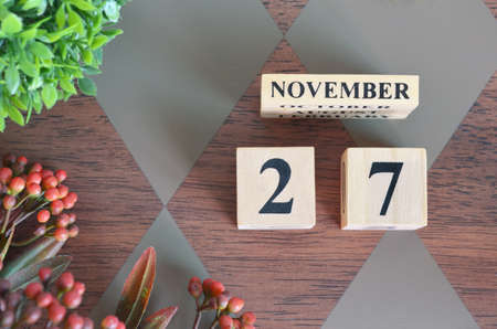November 27. Date of November month. Number Cube with flower leaves and bush on Diamond wood table for the backgroundの写真素材
