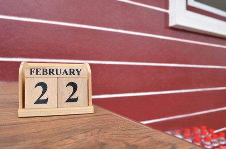 February 22, Number cube with a wooden table beside the wall.の写真素材