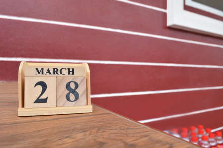 March 28, Number cube with wooden table beside the wall.の写真素材