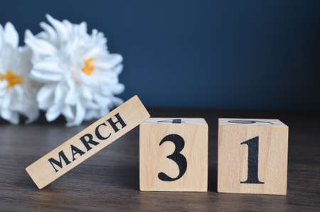March 31, Date cover design with calendar cube and white Paeonia flower on wooden table and blue background.の写真素材