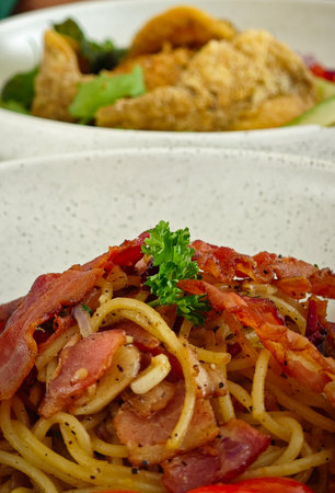 Spaghetti carbonara with bacon and vegetables in a white plate.の写真素材