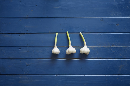 three cloves of garlic on blue wooden tableの写真素材