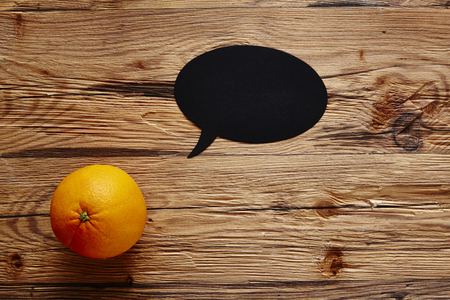 orange with speech bubble on wooden boardの写真素材