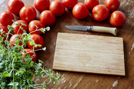 cutting board and knife with tomatoes and herbsの写真素材