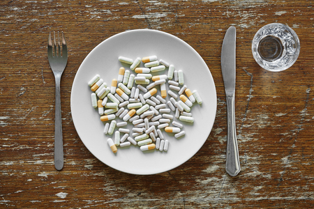 a bunch of pills on plate knife and forkの写真素材