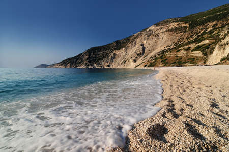 Foamy water coming on beach with small stones.の写真素材