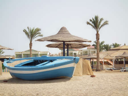 Old boat on the sandy beach with palm treesの写真素材