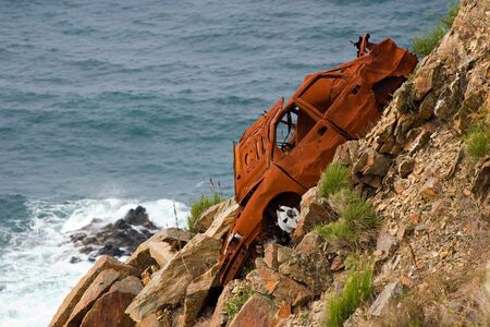 oxidized rest of a car left in a cliffの写真素材