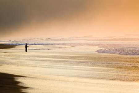 silhouette of fisherman in a beach to the duskの写真素材