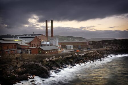 Factory in the shore of the sea illuminated by the last beams of the dayの写真素材