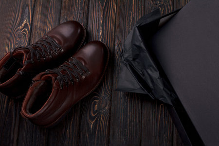 Men's lether boots on the brown wooden table overhead view. Shoe with shoe boxの写真素材