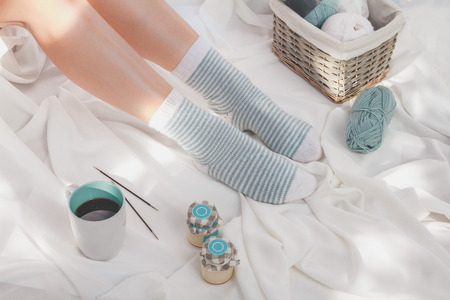 Warm and cozy striped socks on women legs and basket with knitting yarnの写真素材