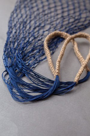 Modern handmade dark blue empty string shopping bag from low perspective on gray paper background....