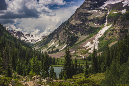 Beautiful Maroon Bells and Crater Lake in Snowmass Wilderness in Aspen, Colorado with a blue sky and clouds in summerの写真素材