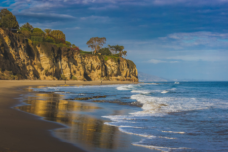 Beachside view of beautiful blue Pacific Ocean and stunning cliffs surrounding Dume Cove on a sunny day with clouds in the sky, Point Dume, Malibu, Californiaの写真素材