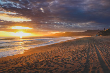 Beautiful coastal sunset on an empty Point Dume State Beach with colorful clouds in the sky and Santa Monica Mountains in the background, Malibu, Californiaの写真素材