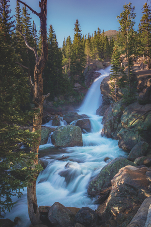 Long-exposure shot of silky smooth water from Alberta Falls cascading down the mountain, Rocky Mountain National Park, Coloradoの写真素材