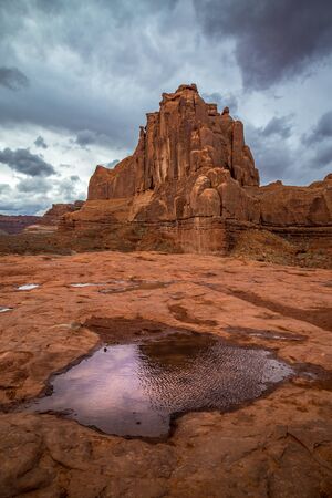 Massive sandstone rock towers in the Park Avenue Section of Arches National Park with dramatic storm clouds looming overhead, Moab, Utahの写真素材