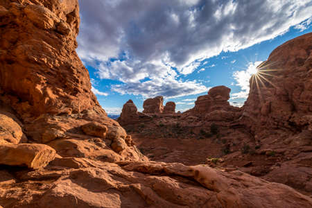 Gorgeous view atop of Turret Arch surrounded by tall sandstone spires and puddles of water that reflect the cloudy blue sky, Arches National Park, Moab, Utahの写真素材
