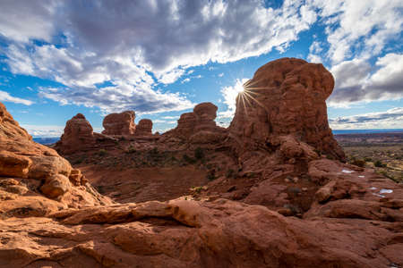 Gorgeous view atop of Turret Arch surrounded by tall sandstone spires and puddles of water that reflect the cloudy blue sky, Arches National Park, Moab, Utahの写真素材